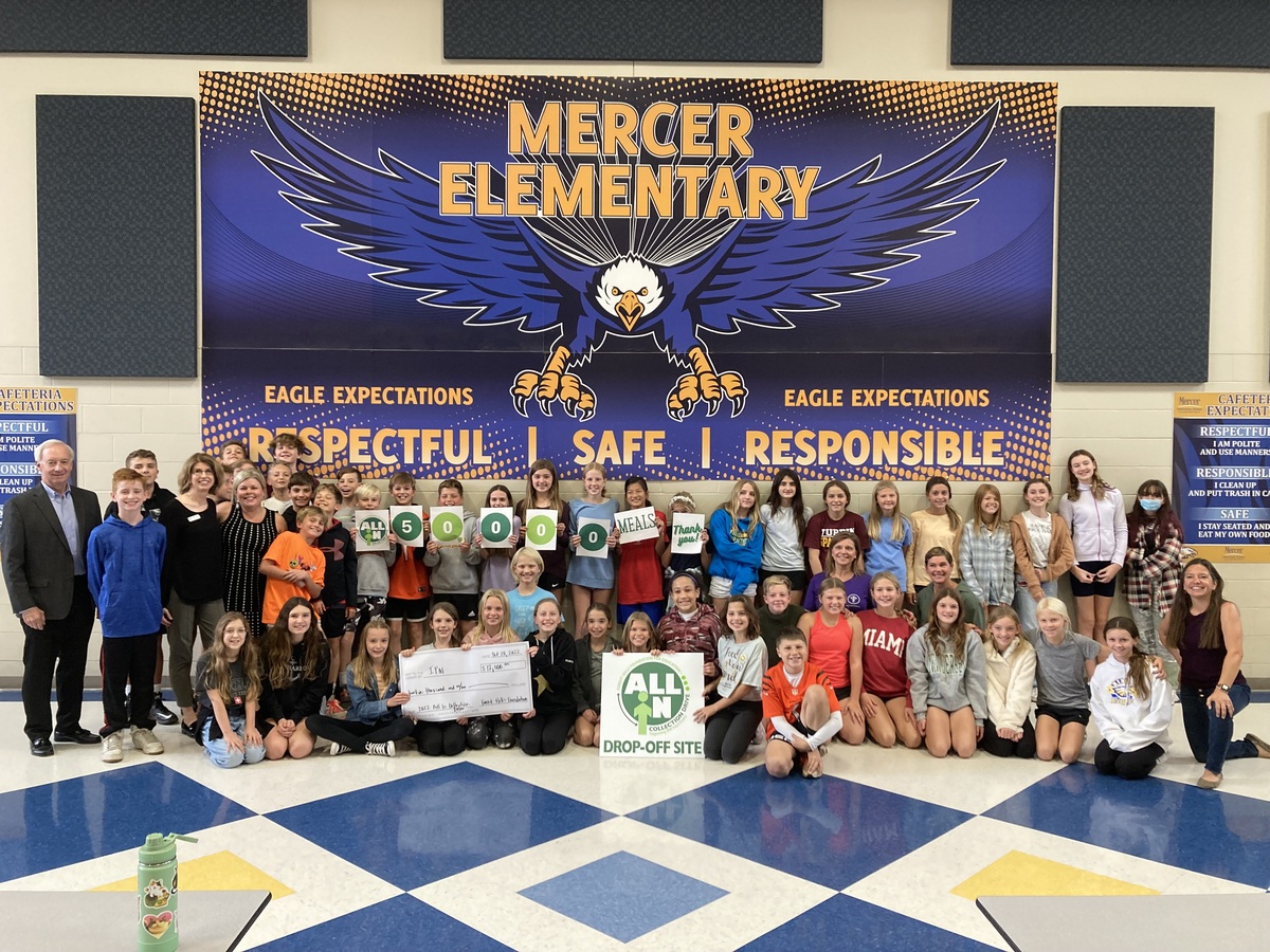 Group holding signs in front of 'Mercer Elementary' banner
