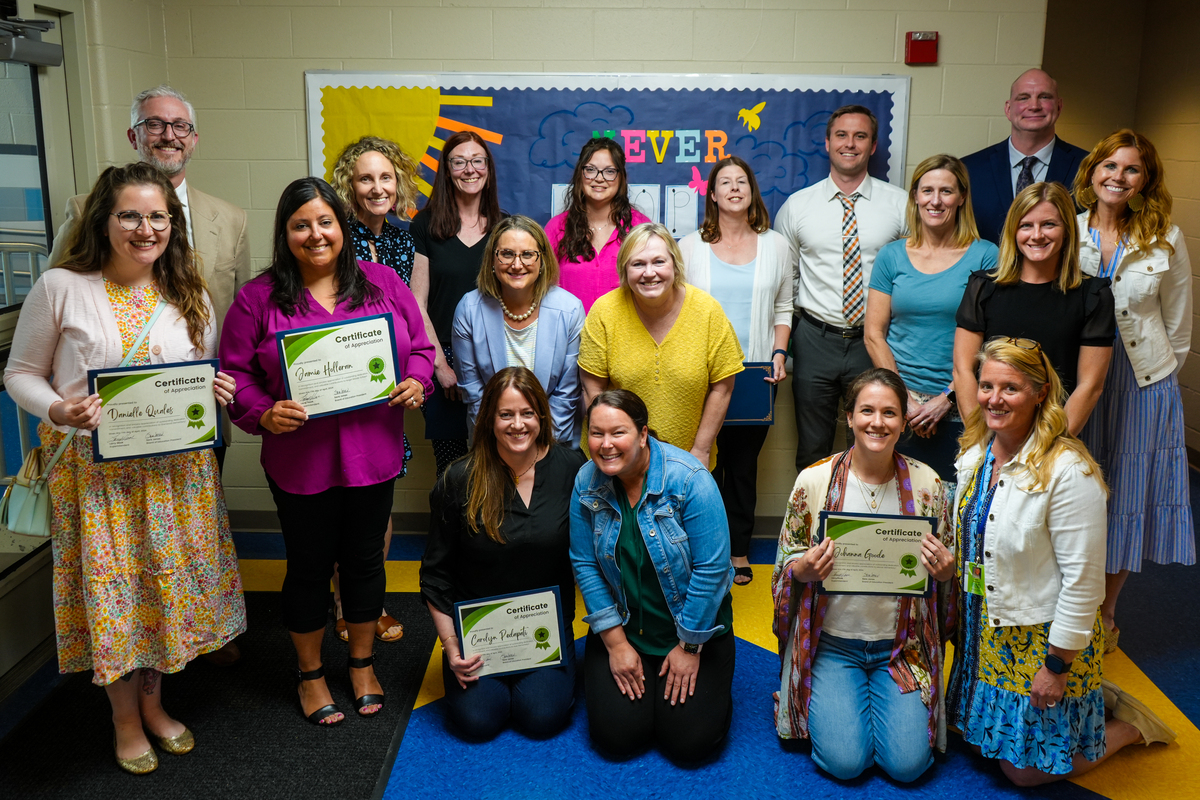 Volunteers pose for a photo with building principals and their certificates of appreciation