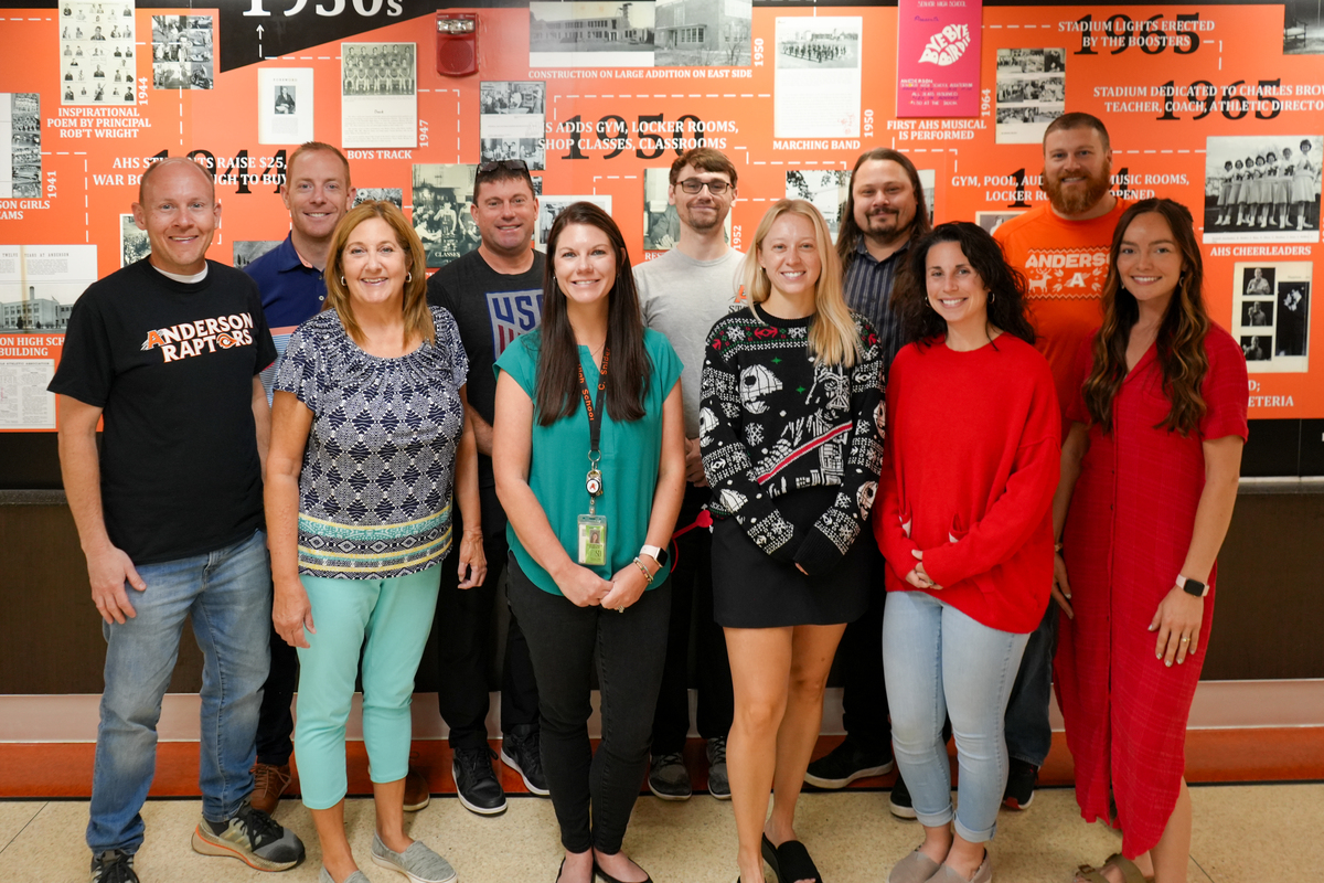 Anderson science teachers pose for a photo in front of the school's history wall