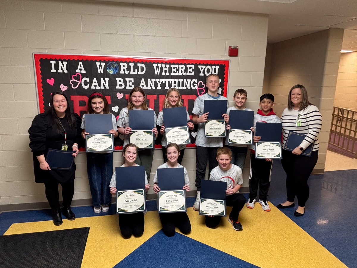 students and teachers pose for a photo while holding certificates