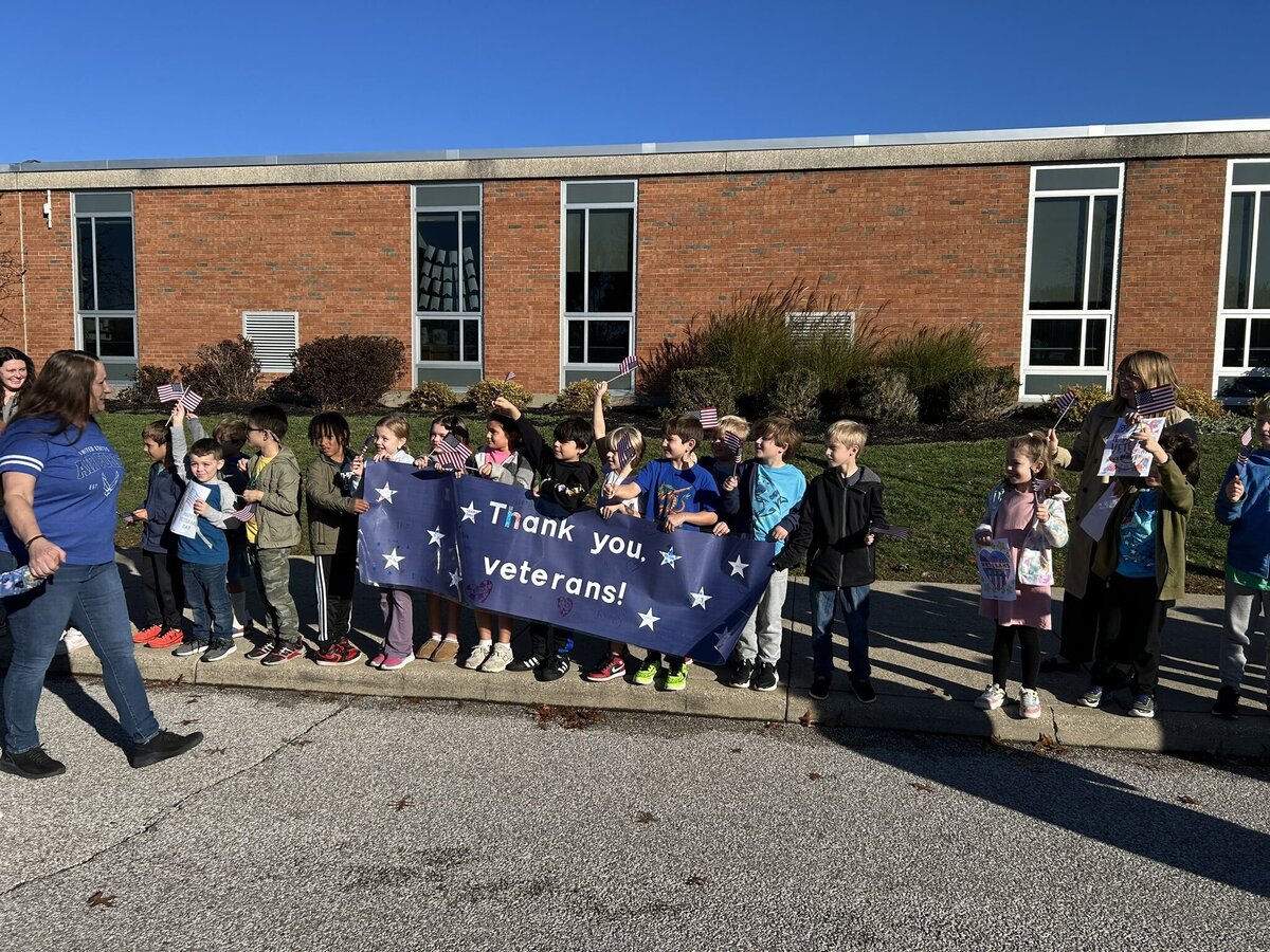 Students hold a sign that says "Thank you veterans" during a Veterans Day at their school